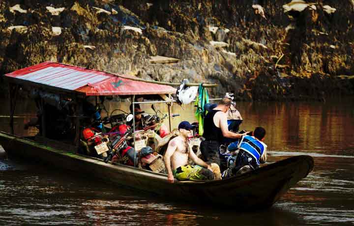 Motorcycle tour group on a boatwith dirt bikes inMae Sariang Thailand